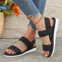 Sandale Femme Confortable et Antidérapante portée par une femme avec un jean bleu et un bracelet de cheville devant un mur avec un panier de fleur à gauche