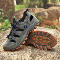 Sandale Sport Homme en Cuir et Antidérapante posée sur un rocher avec des plantes vertes en fond et d'autres rochers