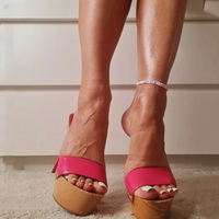 Sandale Talon Haut Femme avec Semelle en Bois portée par une femme avec un bracelet de cheville sur un tapis avec un meuble derrière elle