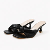 Sandales noires élégantes à bout carré, faciles à enfiler, avec larges brides croisées et talons hauts évasés.