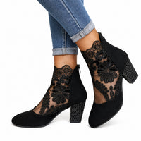 Bottine femme mariage noire avec motif floral en dentelle. La chaussure présente un talon carré noir de hauteur moyenne d'environ 5-7 cm orné de petits strass/clous dorés, un corps en velours suédé noir, une fermeture éclair latérale noire, une décoration spectaculaire de dentelle noire ajourée avec motifs floraux baroques sophistiqués qui couvre les côtés créant un effet de résille transparente très élégant, doublage intérieur noir, design très élégant fusion entre bottine et sandale avec effet transparent