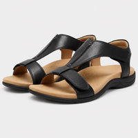 Paire de sandales modernes pour femme, noires avec semelle beige souple et confortable, dotées de larges brides croisées et d’un léger talon compensé.