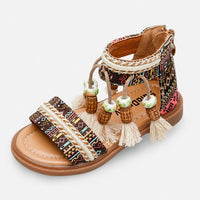 Sandale fille marron à motifs ethniques colorés, avec larges brides décoratives, lanière à la cheville, pompons et pampilles en perles, fermeture zippée à l’arrière