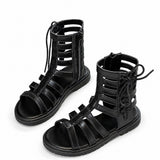 Sandales montantes noires pour fille avec lanières ajourées, lacets et fermeture éclair, au design moderne et tendance.