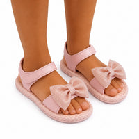 Sandales fille rose clair avec grandes nœuds papillon scintillants sur les brides, fermeture à scratch et semelle tressée.