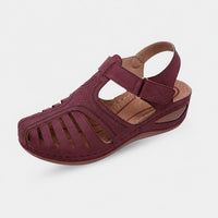 Sandale femme bordeaux à talon compensé, avec bride à scratch, boucle ajustable et détails ajourés pour un confort élégant.
