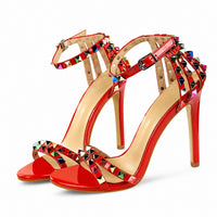 Sandale Cloutée Style Escarpin avec Lanière de Cheville rouge avec brides ornées de clous pyramidaux multicolores, boucle réglable à la cheville, bout ouvert et talon aiguille pour un style chic et élégant.