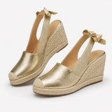 Sandale Compensée Femme en Simili Cuir avec un Nœud, finition dorée métallisée, bride arrière nouée, semelle compensée en corde et design élégant.