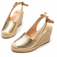 Sandale Dorée à Talon Haut Compensé avec finition métallisée dorée, talon compensé effet corde tressée, bout fermé et bride arrière à nouer pour un style estival élégant.