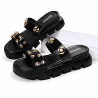 Sandale Femme Cloutée avec Semelle Épaisse noire avec doubles brides ornées de clous dorés, bout ouvert, semelle épaisse crantée et design moderne pour un style tendance et confortable.