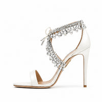 Sandale de mariage pour femme en satin blanc à talons hauts fins, ornée de faux diamants scintillants et d'une bride à la cheville, présentée sur fond blanc.