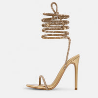 Sandale Gladiator à Talon Haut avec Fermeture à Lacets Dorés, fines lanières dorées à nouer autour de la jambe, bride entre-doigts, talons aiguilles et design glamour