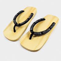 Sandale Japonaise Style Tong avec Lanières Noires en bois naturel avec lanières en tissu noir à inscription blanche, design traditionnel japonais et semelle confortable pour un usage quotidien.