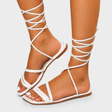 Sandale à Lanière Femme Robuste et Plate, avec fines lanières tressées, lacets à nouer autour de la jambe, semelle plate confortable et design gladiateur estival