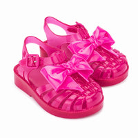 Sandale Méduse Bébé Rose Fushia avec Nœud Papillon avec matière transparente, grand nœud décoratif, bride réglable à boucle, bout fermé ajouré et semelle confortable pour l’été.