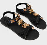 Sandale Plate Femme Noire Bohème avec Détails Dorés Élégants, bride entre-doigts, ornements floraux dorés, bride arrière élastique et design bohème chic