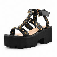 Sandale Talon Plateforme avec Design Clouté noire avec multiples brides ornées de clous dorés, bride réglable à la cheville, semelle plateforme épaisse et talon carré pour un style moderne et tendance.
