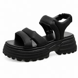Sandale Talon Plateforme avec Fermeture Élastique noire avec larges brides croisées, bride arrière élastique, semelle plateforme épaisse crantée et design moderne pour un style confortable et tendance.