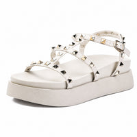 Sandale Talon Plateforme avec Lanières Cloutées Blanches avec fines brides ornées de clous pyramidaux métalliques, boucle réglable à la cheville, bout ouvert et semelle plateforme épaisse pour un style moderne et tendance.