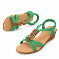 Sandale Verte Femme avec Bande Élastique avec brides croisées vertes, bande élastique à la cheville, détails décoratifs dorés, semelle compensée confortable et design estival élégant.