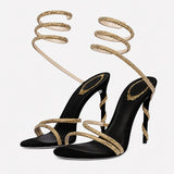 Sandales À Talon Femme Avec Brides Spirales Chic noires avec fines brides dorées scintillantes, lanières spirales autour de la cheville, bout ouvert et talon aiguille pour un style élégant et raffiné.