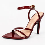 Sandales à talons hauts pour femme en cuir verni bordeaux avec bride à la cheville, bout carré et talon aiguille, présentées sur fond blanc.