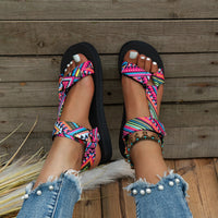 Sandale Scratch Femme Design avec Lanières Multicolores à Motifs sur les pieds d'une femme sur fond de bois